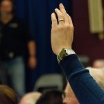 People raising hands to vote in a community setting