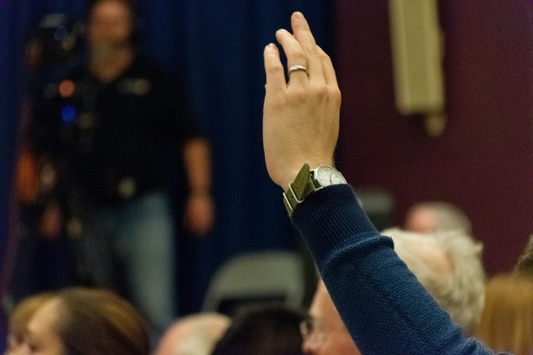 People raising hands to vote in a community setting