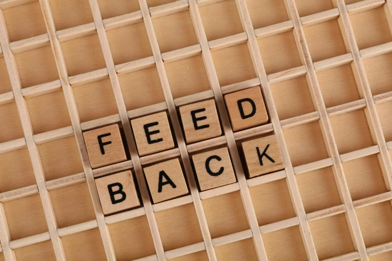 Wooden letter blocks spelling Feedback on a wooden grid surface representing community feature request boards