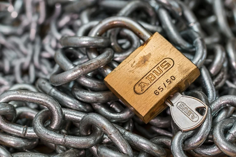 Brass padlock with key on steel chains symbolizing role-based permissions and access control for membership sites