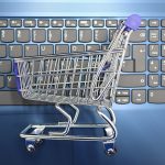 Miniature shopping cart on laptop keyboard representing adding a discussion forum to a WooCommerce online store