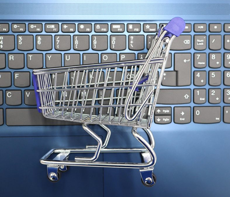 Miniature shopping cart on laptop keyboard representing adding a discussion forum to a WooCommerce online store