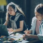Two team members collaborating on a project with laptops representing community forum teamwork