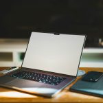 Laptop on wooden desk in home office workspace for community forum participation