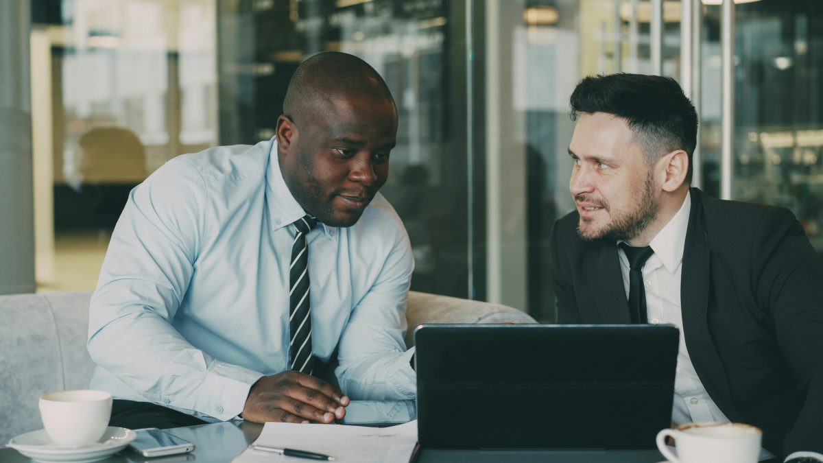 Two business colleagues discussing community strategy at laptop in modern office