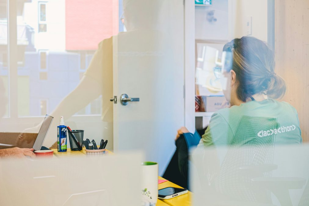 Woman working at desk through glass managing online community forum