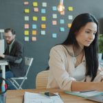 Businesswoman using laptop taking notes for community forum content management