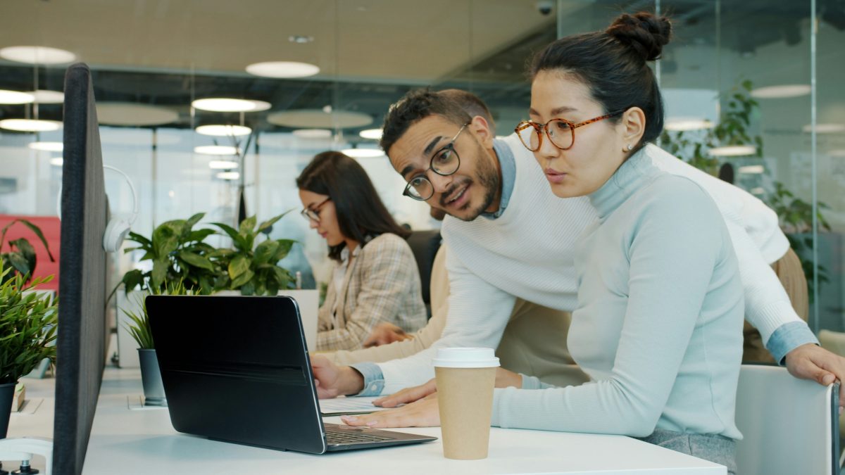 Two colleagues collaborating on a laptop discussing online community and forum strategy