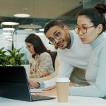 Two colleagues collaborating on a laptop discussing online community and forum strategy